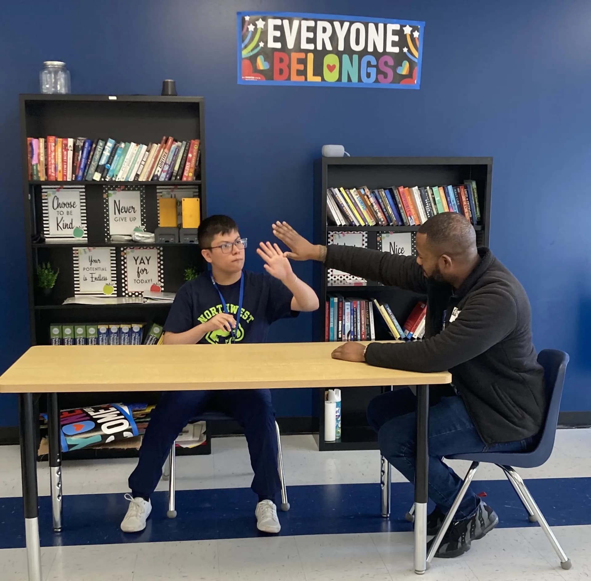 A student and educator high-fiving in an inclusive classroom